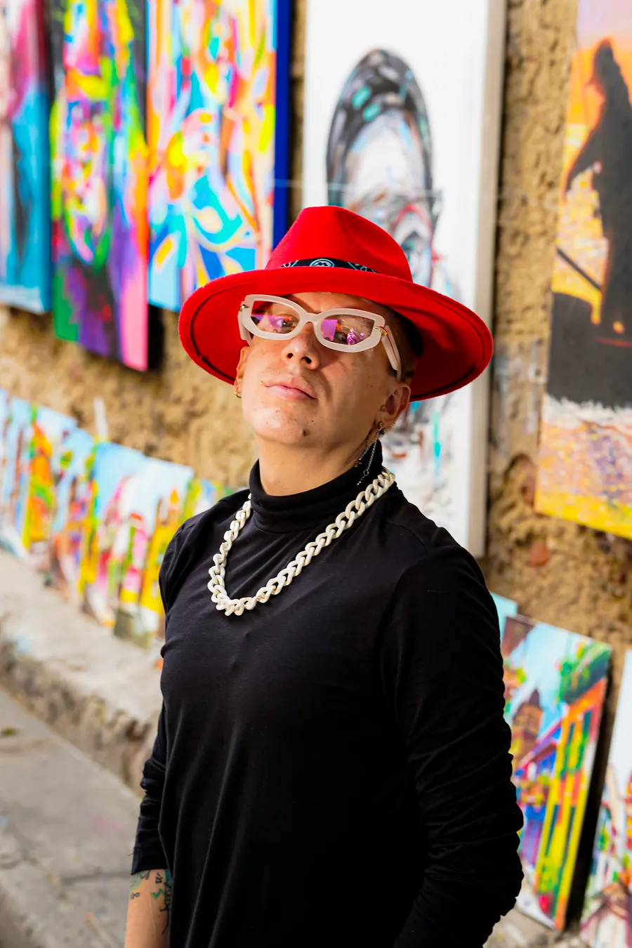 El Rocha con sombrero rojo y cadena entre murales